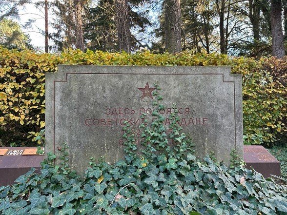 A stone tombstone with ivy growing on it

Description automatically generated